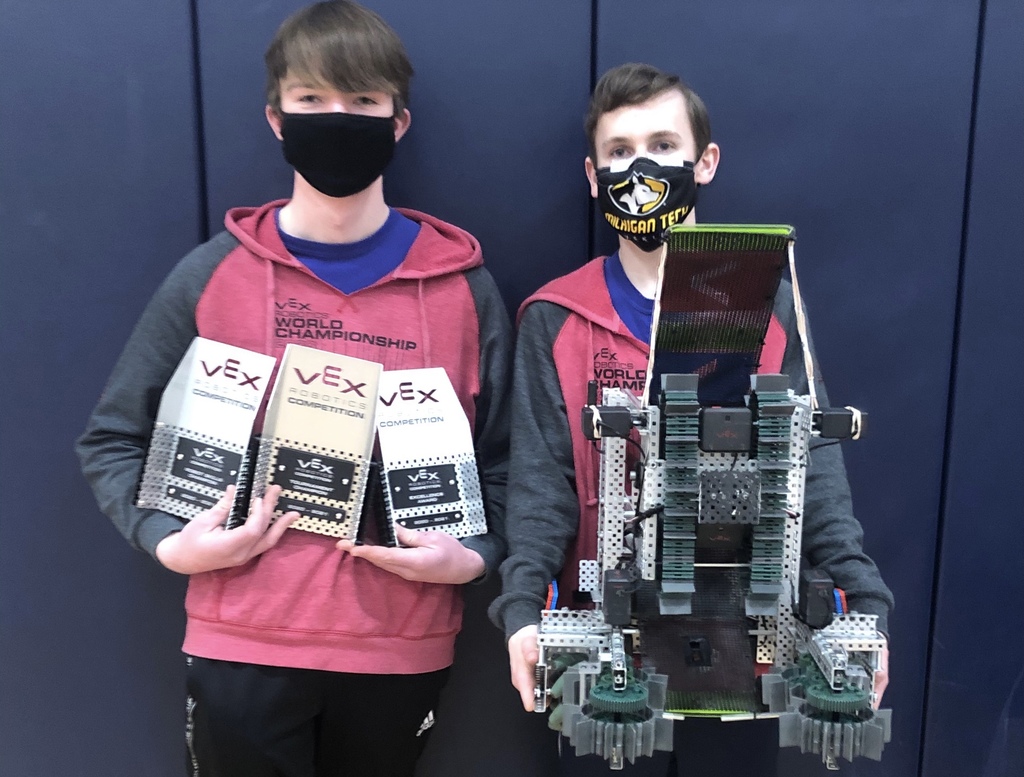 Two boys holding trophies and a robot